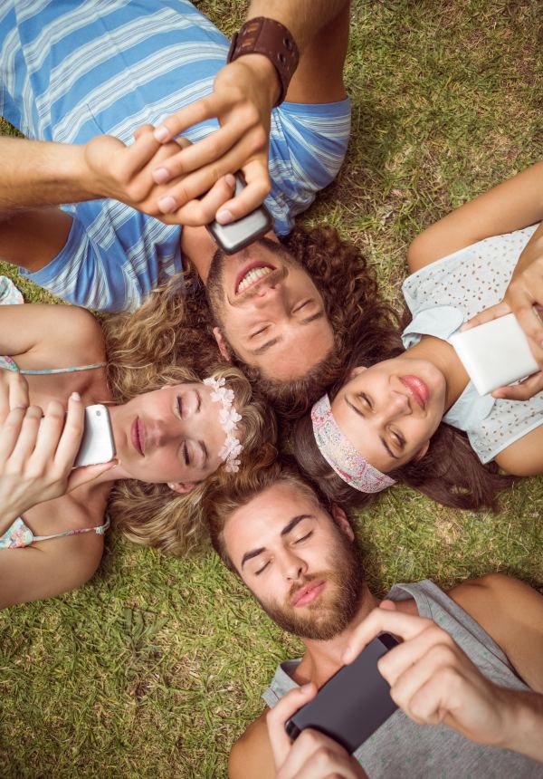 Amis allongés en cercle dans l'herbe, têtes réunies